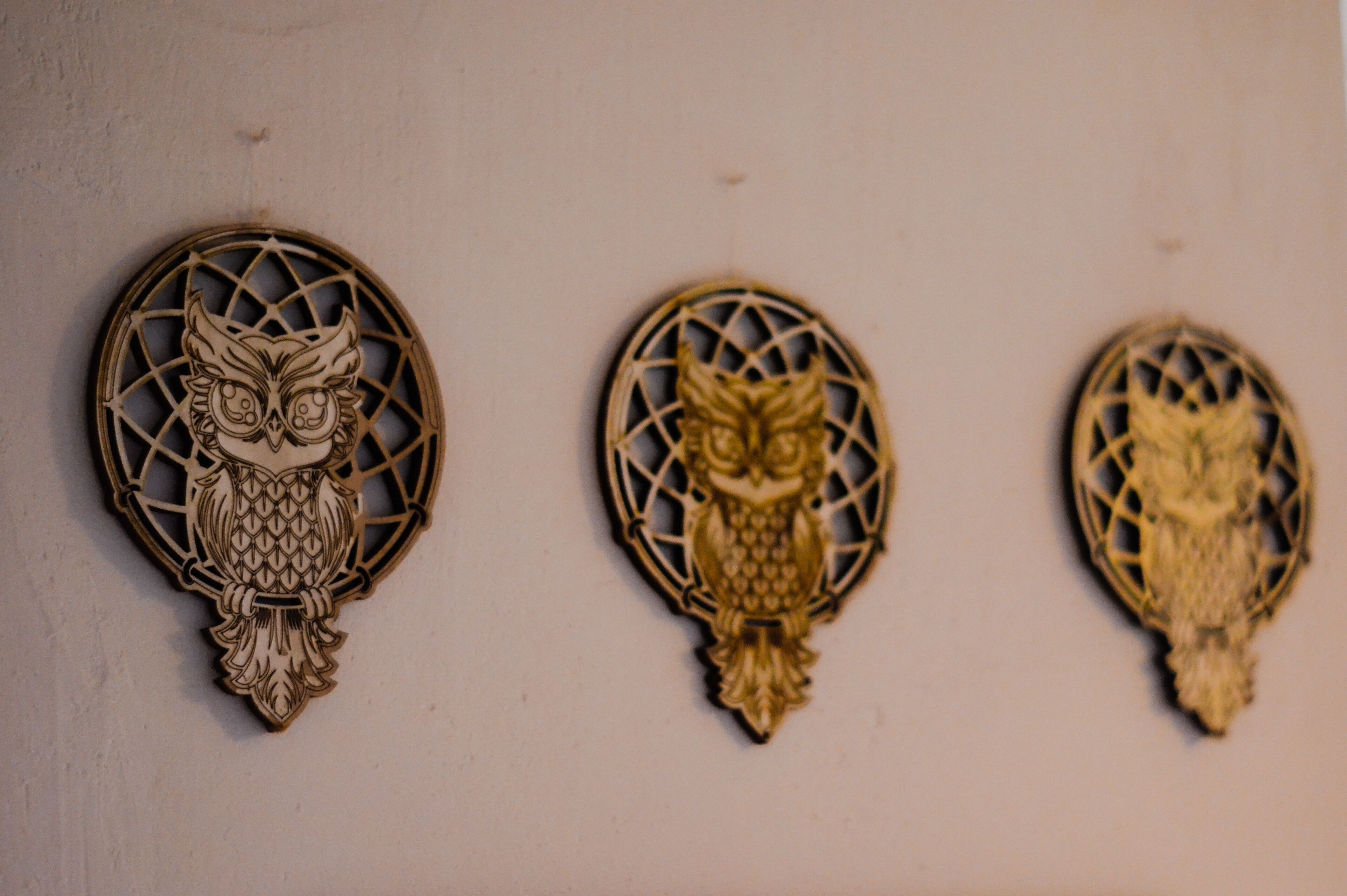 Three wooden wall decorations with owl designs.