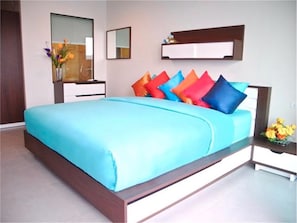 A modern bedroom with a large bed, a nightstand, a dresser, a mirror, and a wall-mounted shelf.