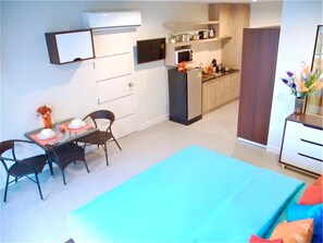 A compact living space with a dining area, kitchenette, and a bed.