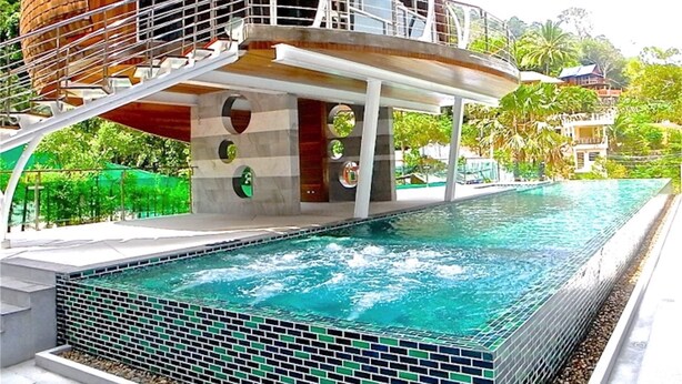 A modern building with a pool, featuring a unique spherical structure and a staircase leading to a balcony.