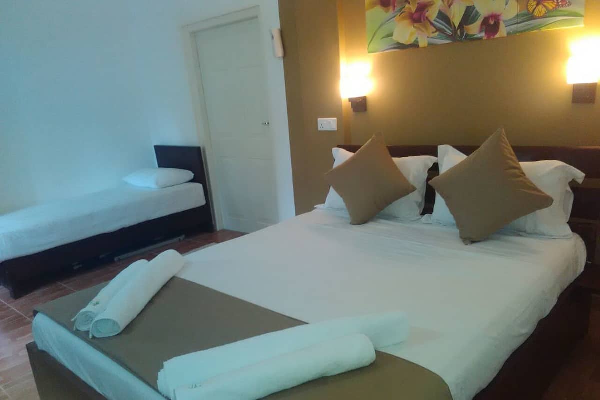 A hotel room with a large bed, two pillows, a bedside table, and a wall-mounted light.