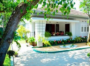 A traditional house with a tiled roof, a porch with potted plants, and a small garden area with a fountain. - Mama Beach Villa (Negombo)