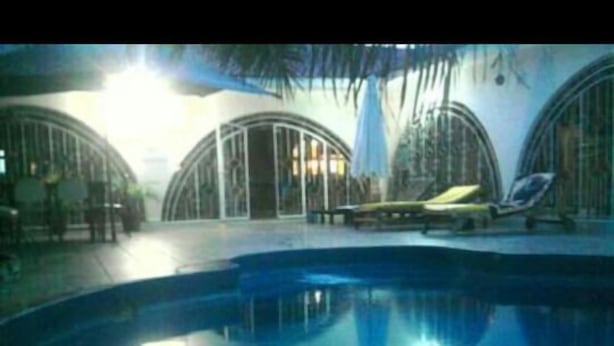 Una piscina con lettini e una zona relax coperta.