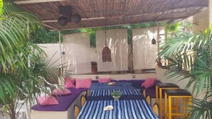 Una zona salotto esterna coperta con tovaglia a righe, sedute imbottite e piante in vaso.