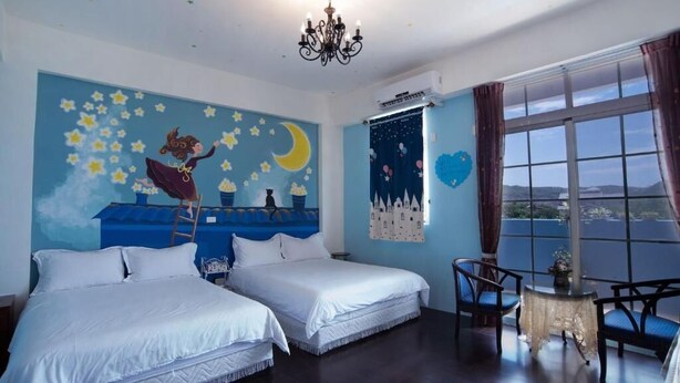 Una habitación con dos camas, una araña, un ventanal con cortinas y un mural en la pared.