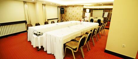 A conference room with a long table, chairs, a projector, and a speaker.