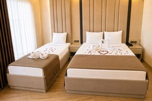 A hotel room with two beds, each with a brown bedspread, white pillows, and a heart-shaped decoration made of rose petals. - Hotel Kayalar (Antalya)