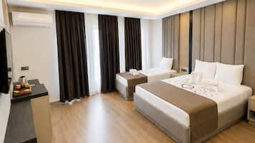 Habitación de hotel moderna con una cama grande, una cama individual, un escritorio con hervidor y un televisor de pantalla plana.