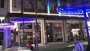 Un hotel a più piani con balconi, condizionatori e un ingresso ben illuminato.
