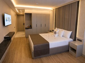 A modern hotel room with a bed, bedside tables, a TV, and a minibar. - Hotel Kayalar (Antalya)