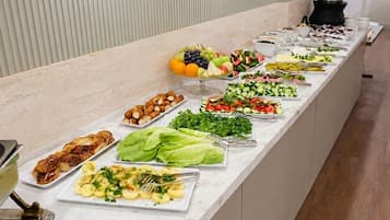 A buffet with various food options including fruits, salads, and cooked dishes.