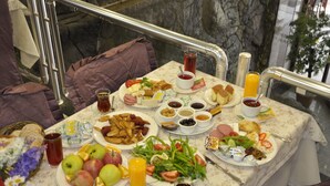 Un buffet della colazione con diversi piatti, bevande e una tovaglia con motivi floreali.
