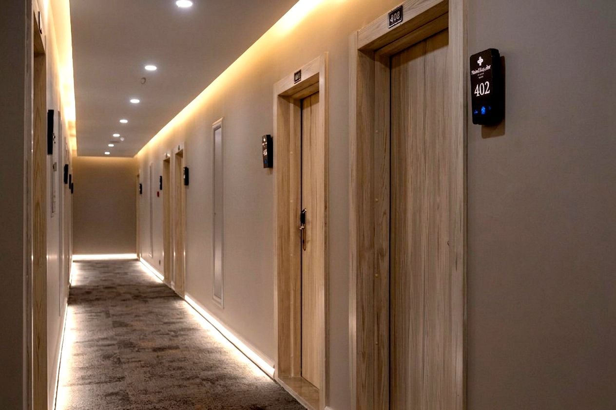 Ein Hotelgang mit Holztüren, nummerierten Zimmern und Teppichboden.