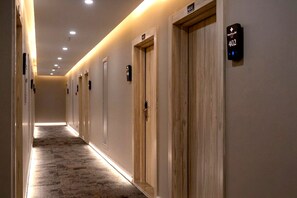 A hotel hallway with wooden doors, numbered room signs, and a carpeted floor. - Hotel Kayalar (Antalya)