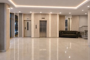 A modern lobby with a polished floor, two elevators, a sofa, and a staircase. - Hotel Kayalar (Antalya)