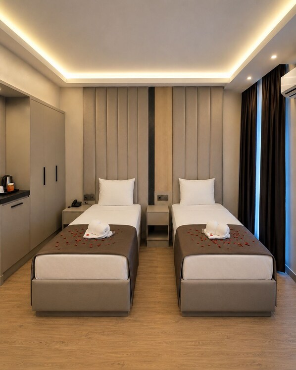 A hotel room with two beds, a desk, a wardrobe, and a view of the city.