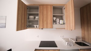 Una cucina moderna con mobili in legno, un piano cottura a induzione nero e una lavastoviglie.