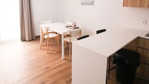 Una cucina moderna con mobili in legno, un piano di lavoro bianco e un'area pranzo con tavolo e sedie.