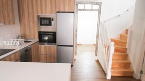 Una cucina moderna con mobili in legno, elettrodomestici in acciaio inossidabile e un piano di lavoro bianco.