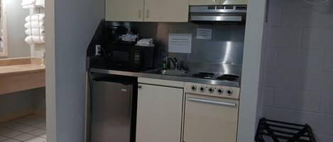 A compact kitchen with a refrigerator, microwave, stove, and sink.