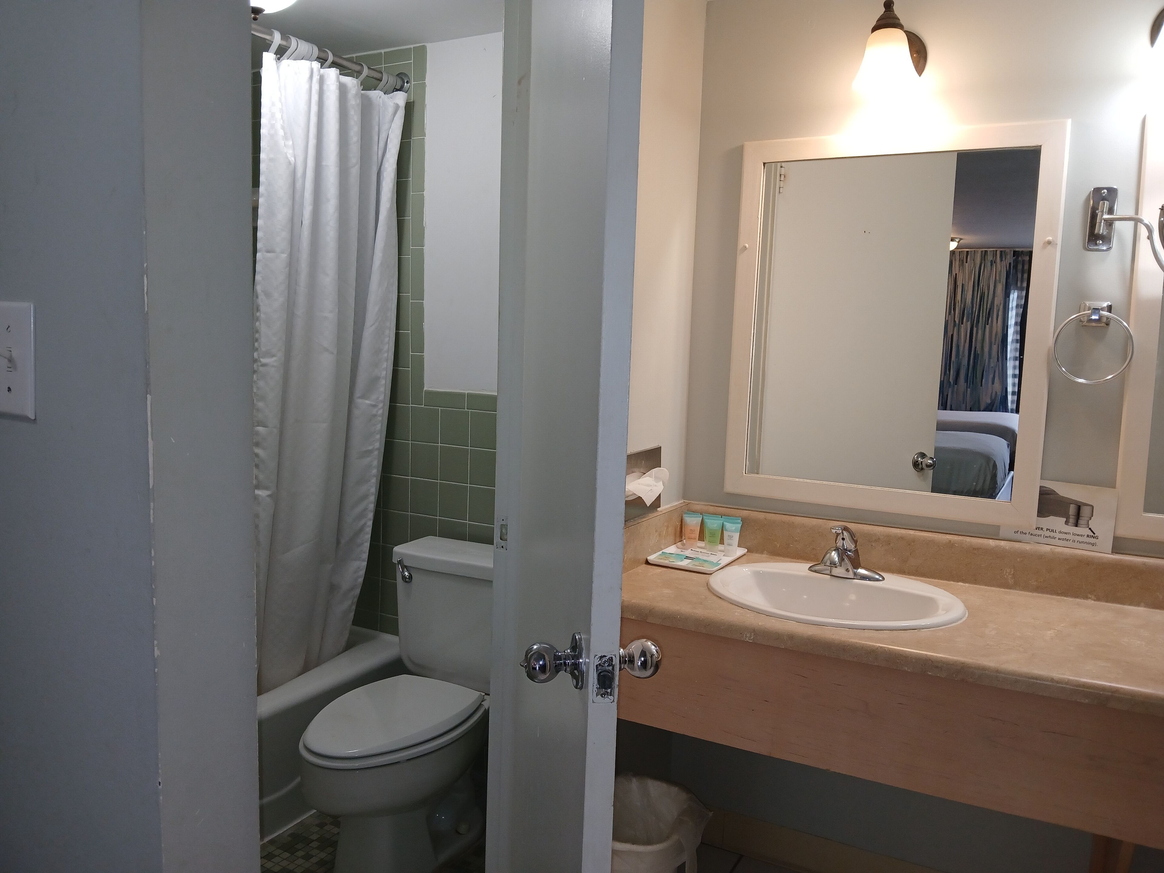 Un baño con inodoro, lavamanos, espejo y cortina de ducha.