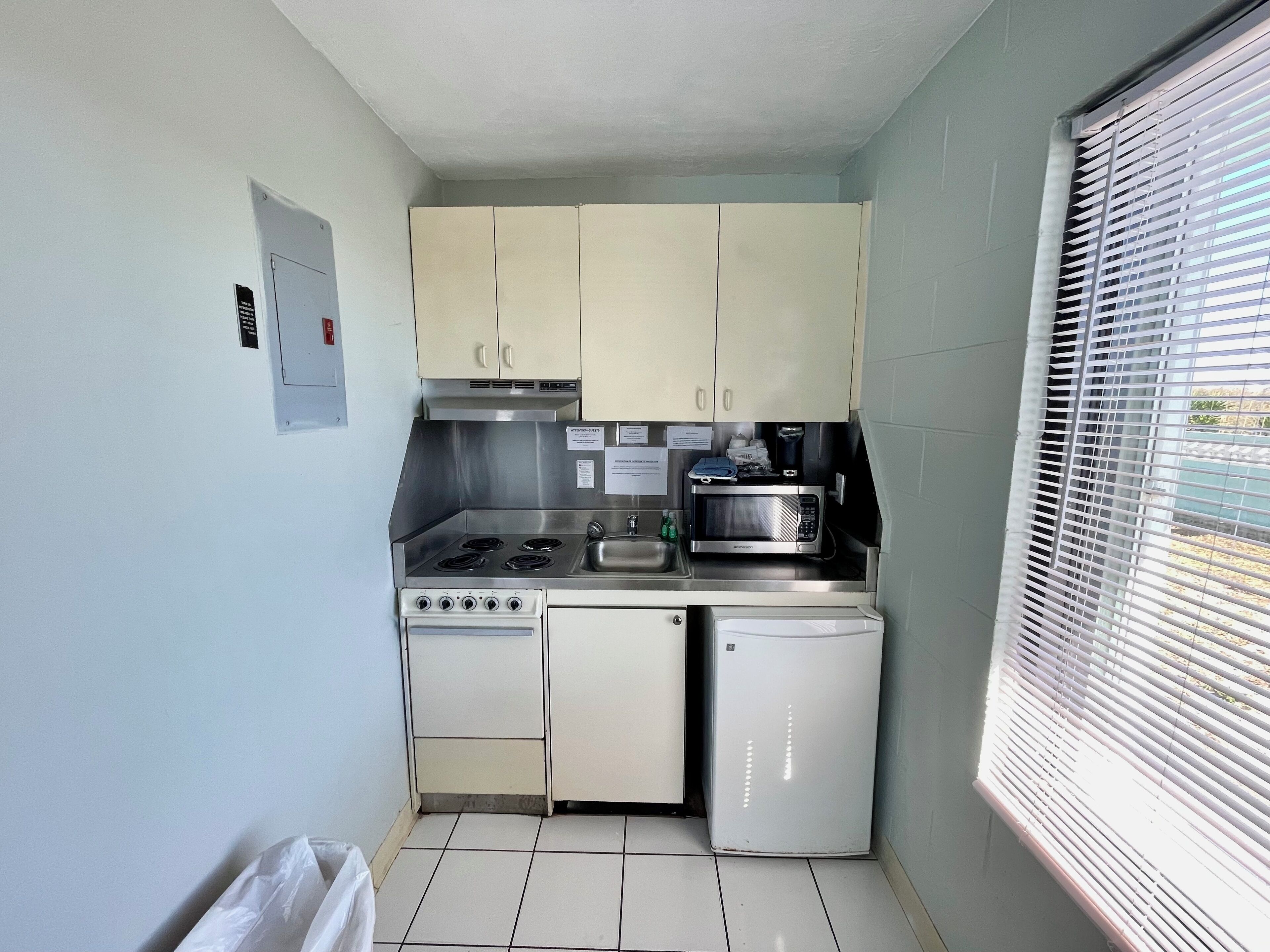 Cozinha compacta com fogão, micro-ondas e lava-louças.