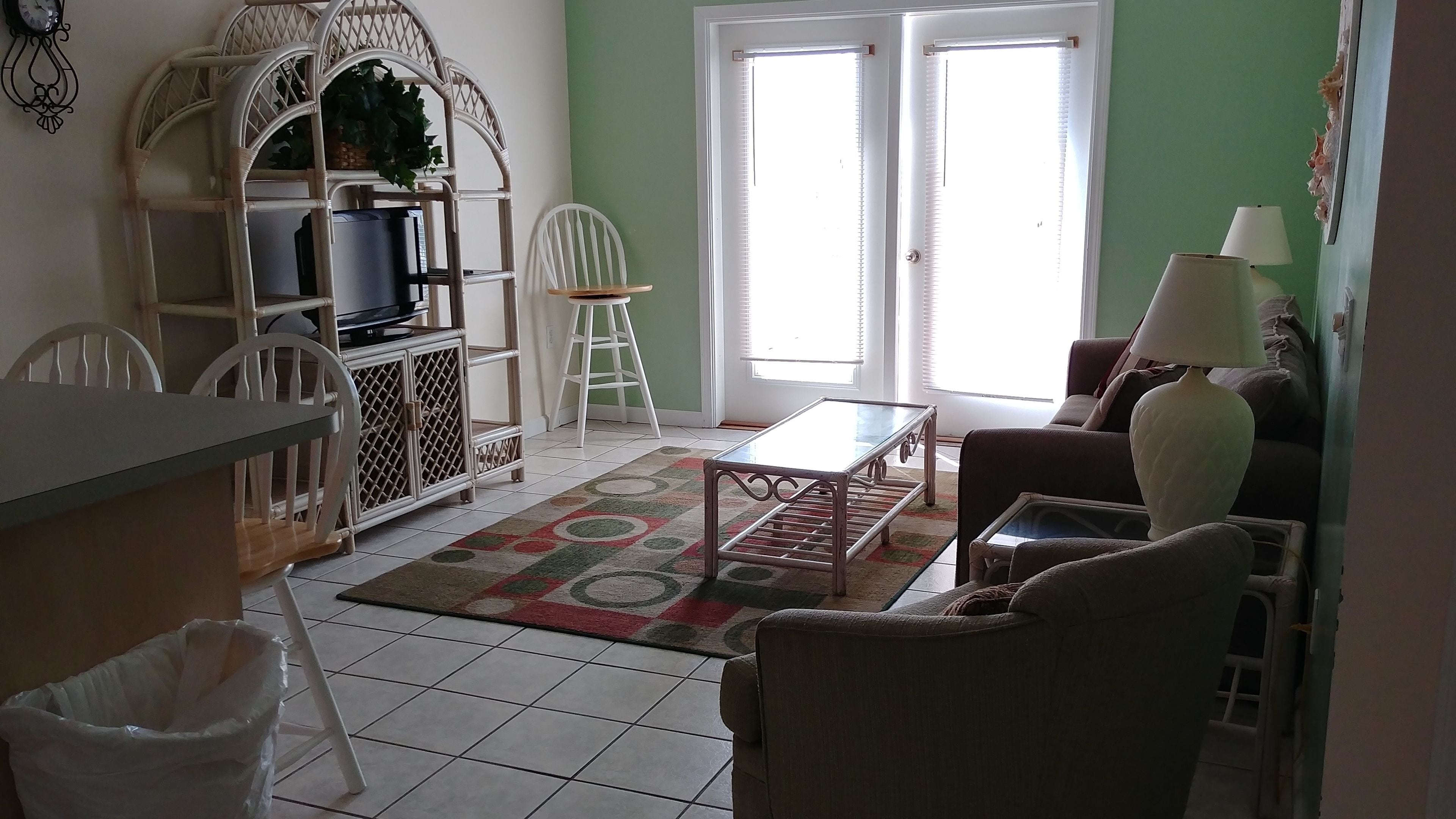 A living room with a television on a white cabinet, a coffee table, a sofa, and a lamp.
