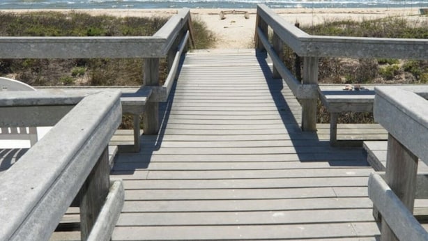 A wooden boardwalk leading to a beach with a clear view of the ocean. - Buccaneer Inn (St. George Island)