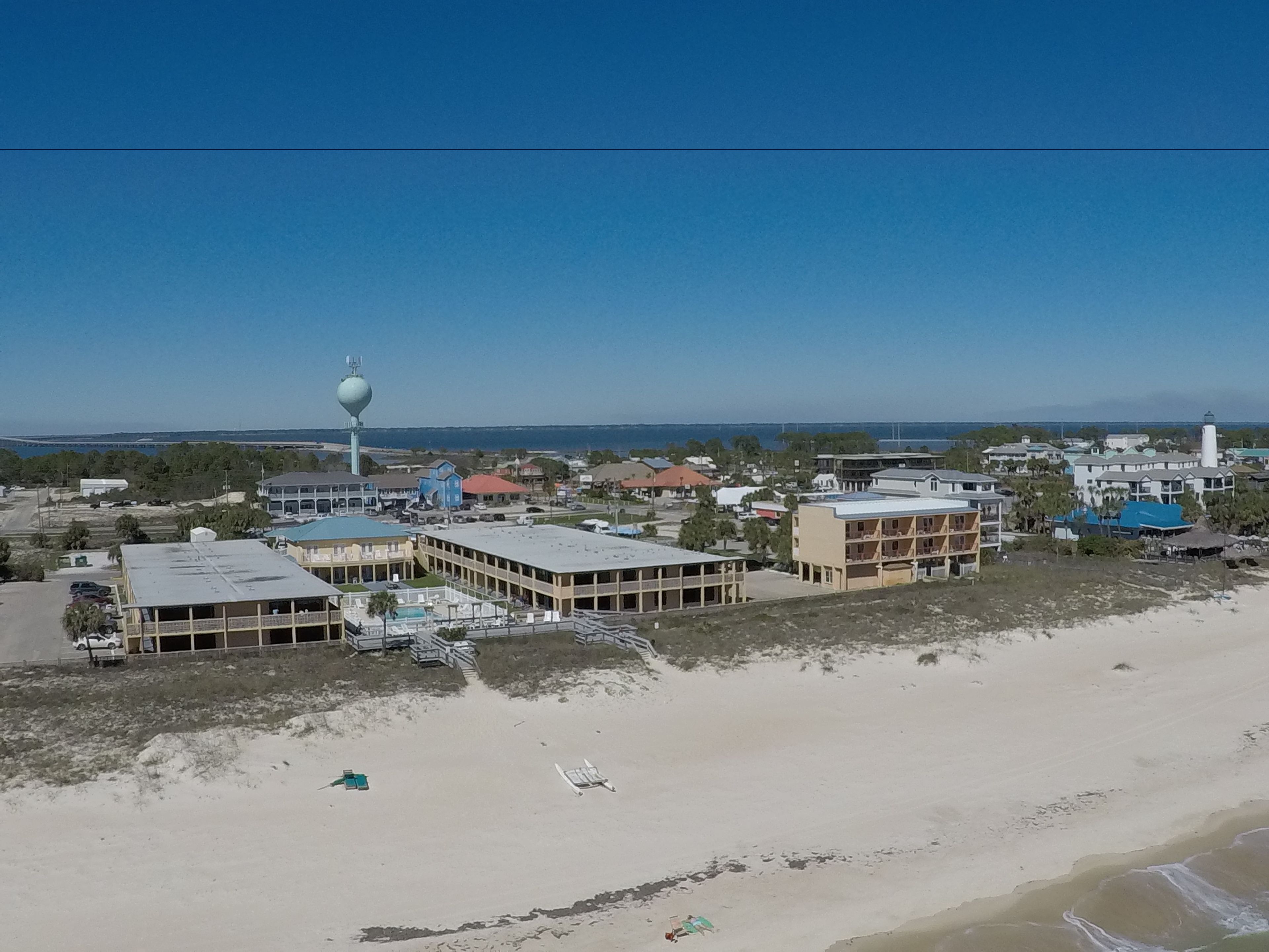 Eine Küstenstadt mit Gebäuden, einem Leuchtturm und einem Strand.