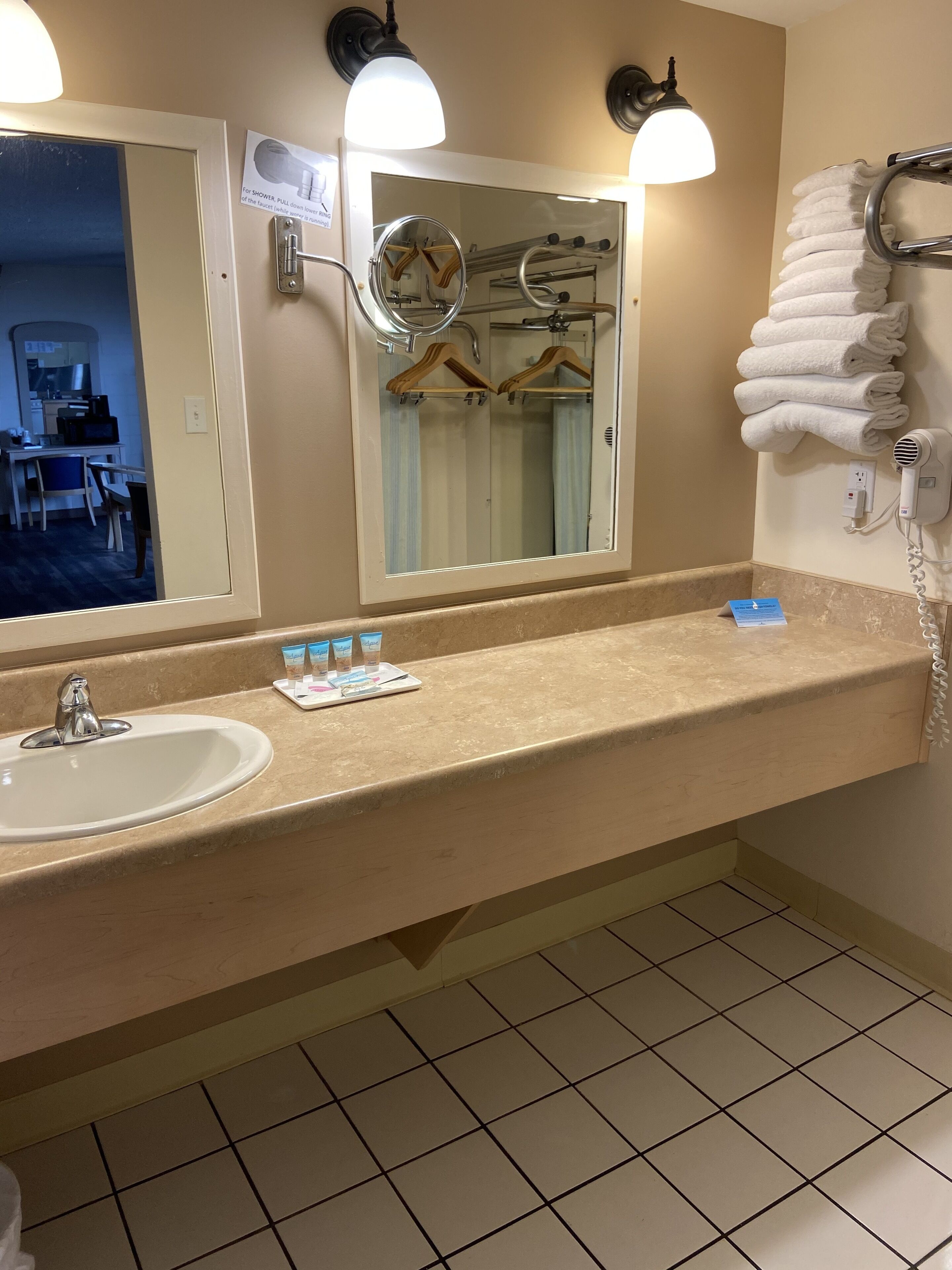 Une salle de bain équipée d’un lavabo, d’un miroir, d’un porte-serviettes et d’un sèche-cheveux.