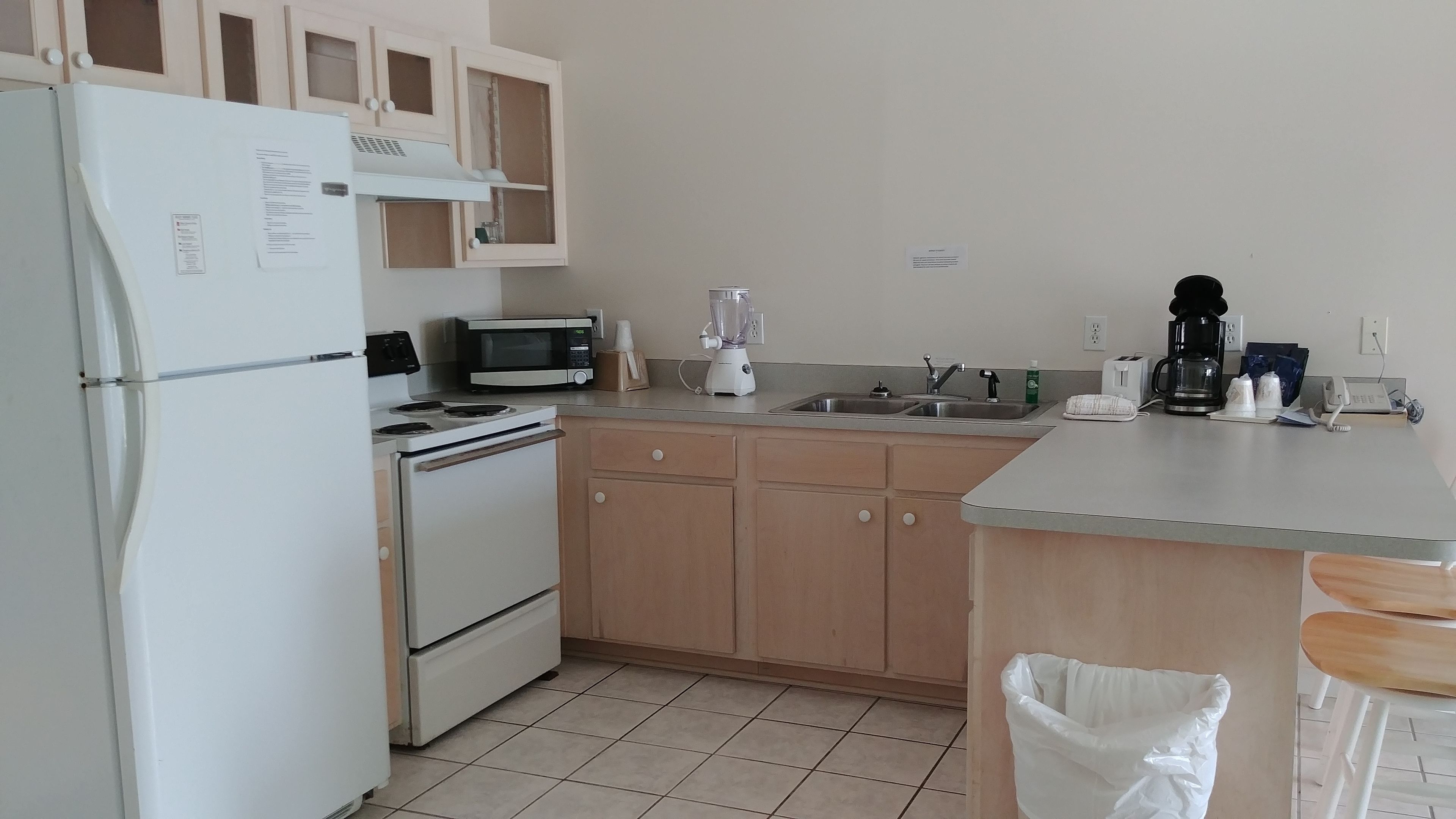 A kitchen with a refrigerator, stove, microwave, sink, and a coffee maker.