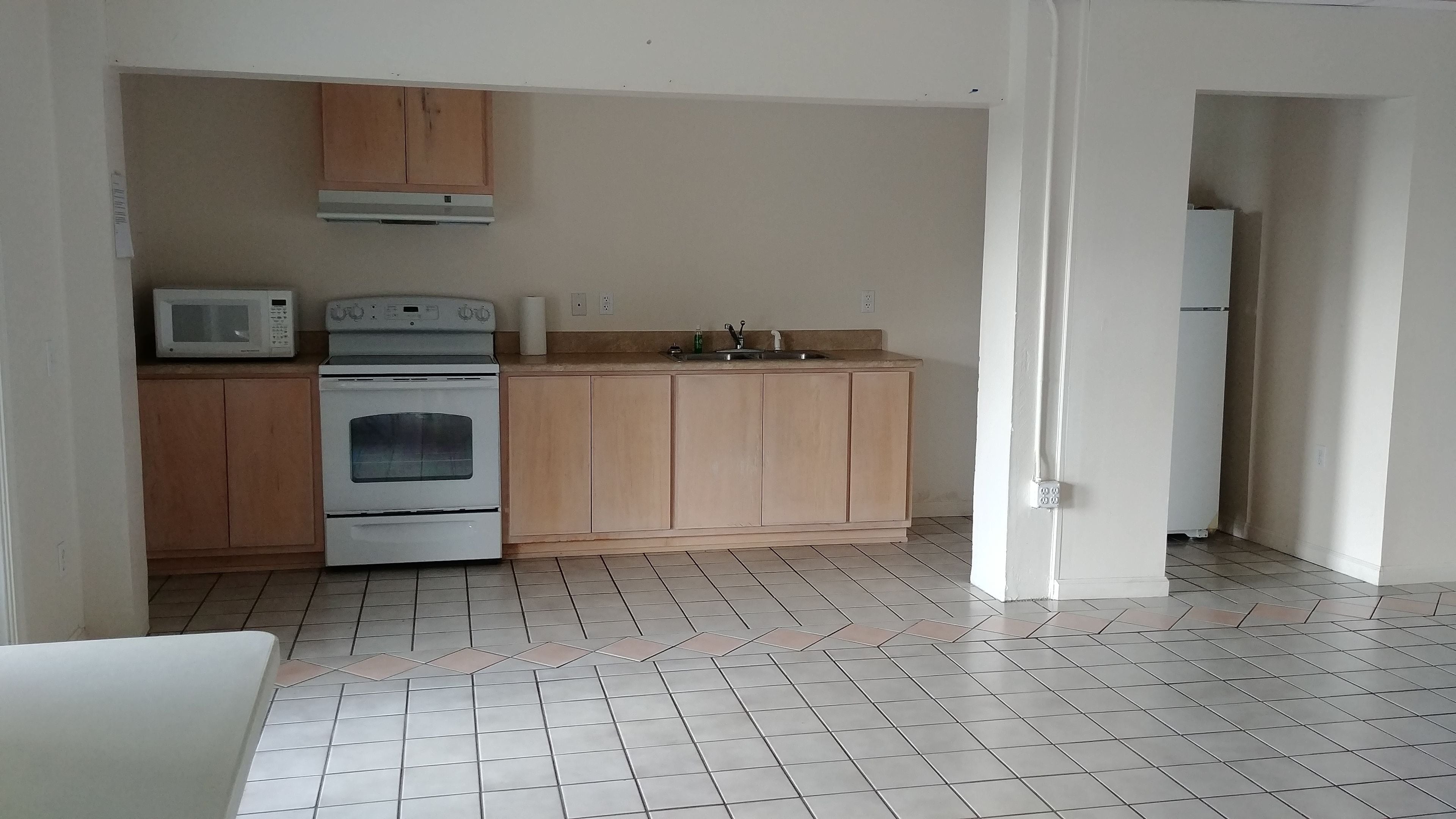 A kitchen with wooden cabinets, a microwave, an oven, and a sink.