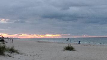 A beach with a cloudy sky and a sunset.