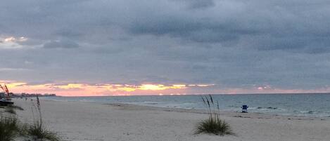 A beach with a cloudy sky and a sunset.