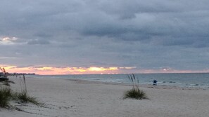 A beach with a cloudy sky and a sunset.