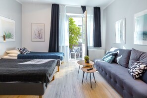 Et moderne hotelværelse med to senge, en sofa, et lille rundt bord og en balkon med udsigt.