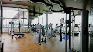 Un gimnasio moderno con diverso equipo de ejercicio, amplias ventanas y suelo de madera.