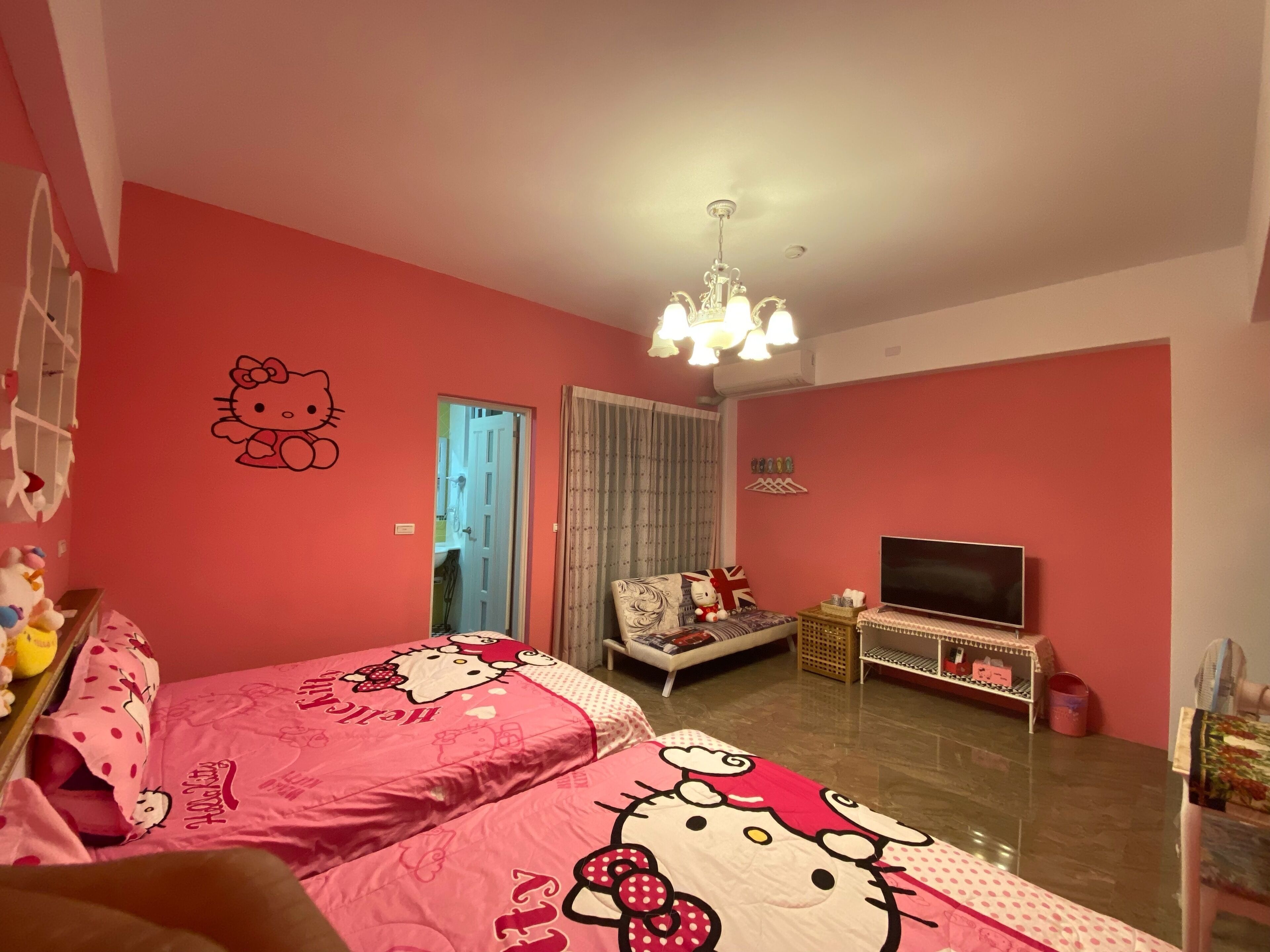 A pink-themed room with two beds, a TV, and a ceiling fan.