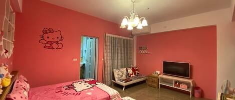 A pink-themed room with two beds, a TV, and a ceiling fan.