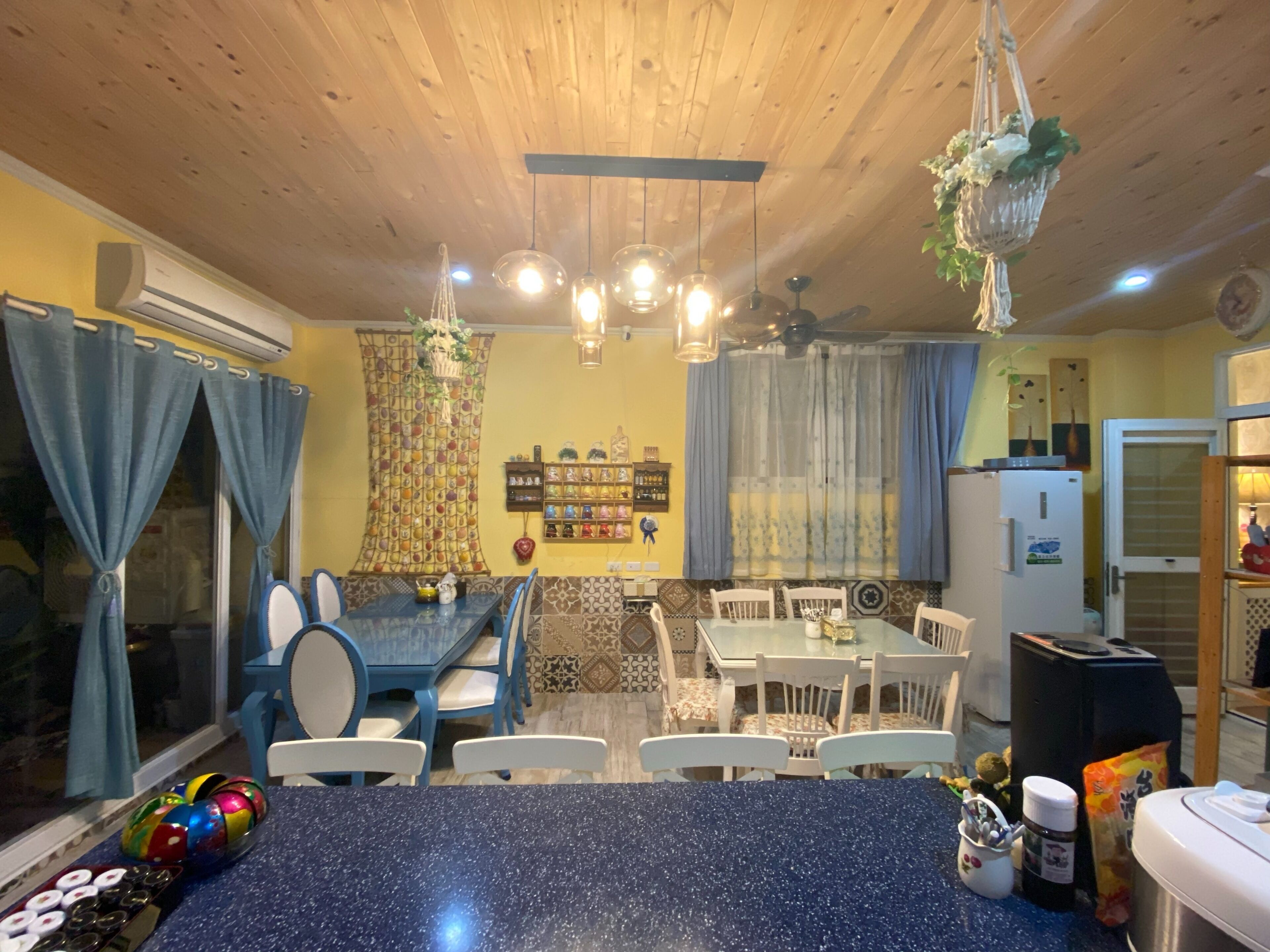 A dining area with a blue speckled table, white chairs, and a chandelier.