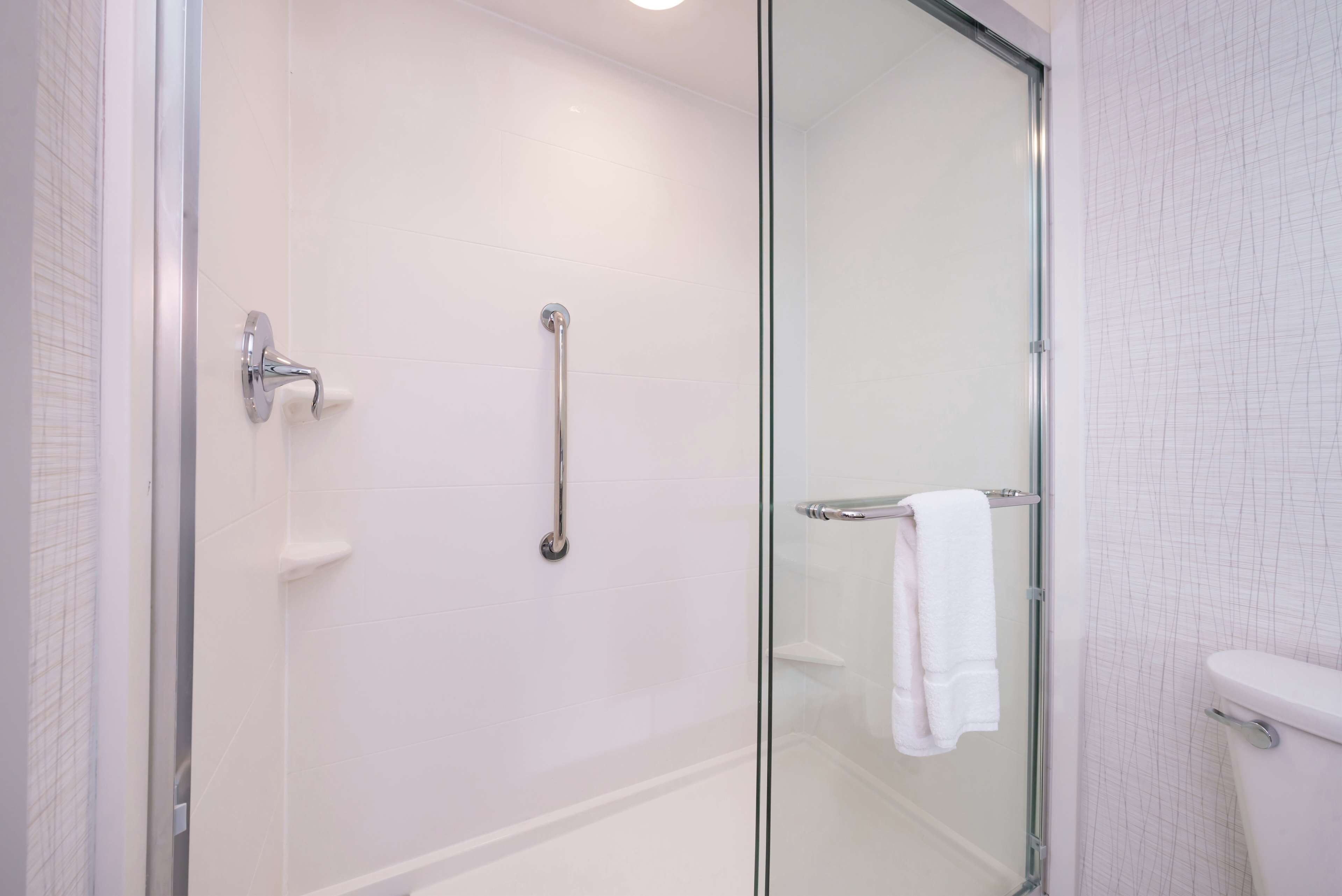 A modern bathroom with a glass shower enclosure, a white toilet, and a glass door.