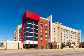 Un hotel moderno con fachada roja y color crema, varios pisos y un letrero llamativo.