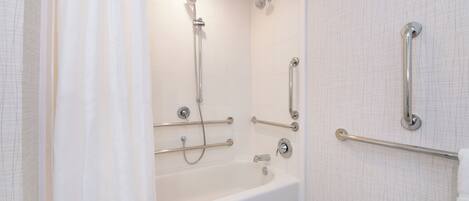 Ein modernes Badezimmer mit Badewanne, Dusche und Haltegriffen.
