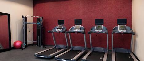 A gym with treadmills, a weight machine, and a red exercise ball.