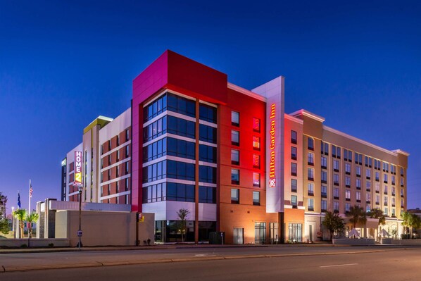 Un hotel de varios pisos con una fachada destacada de rojo y blanco, ventanas amplias y una zona de entrada bien iluminada.