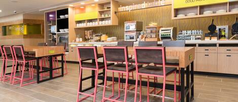 A modern cafe with a wooden counter, pink chairs, and a 'Good Morning' sign.