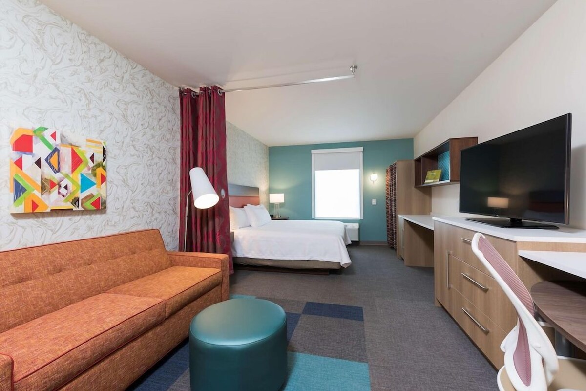 Une chambre d’hôtel avec un canapé, un lit, une télévision et un bureau.