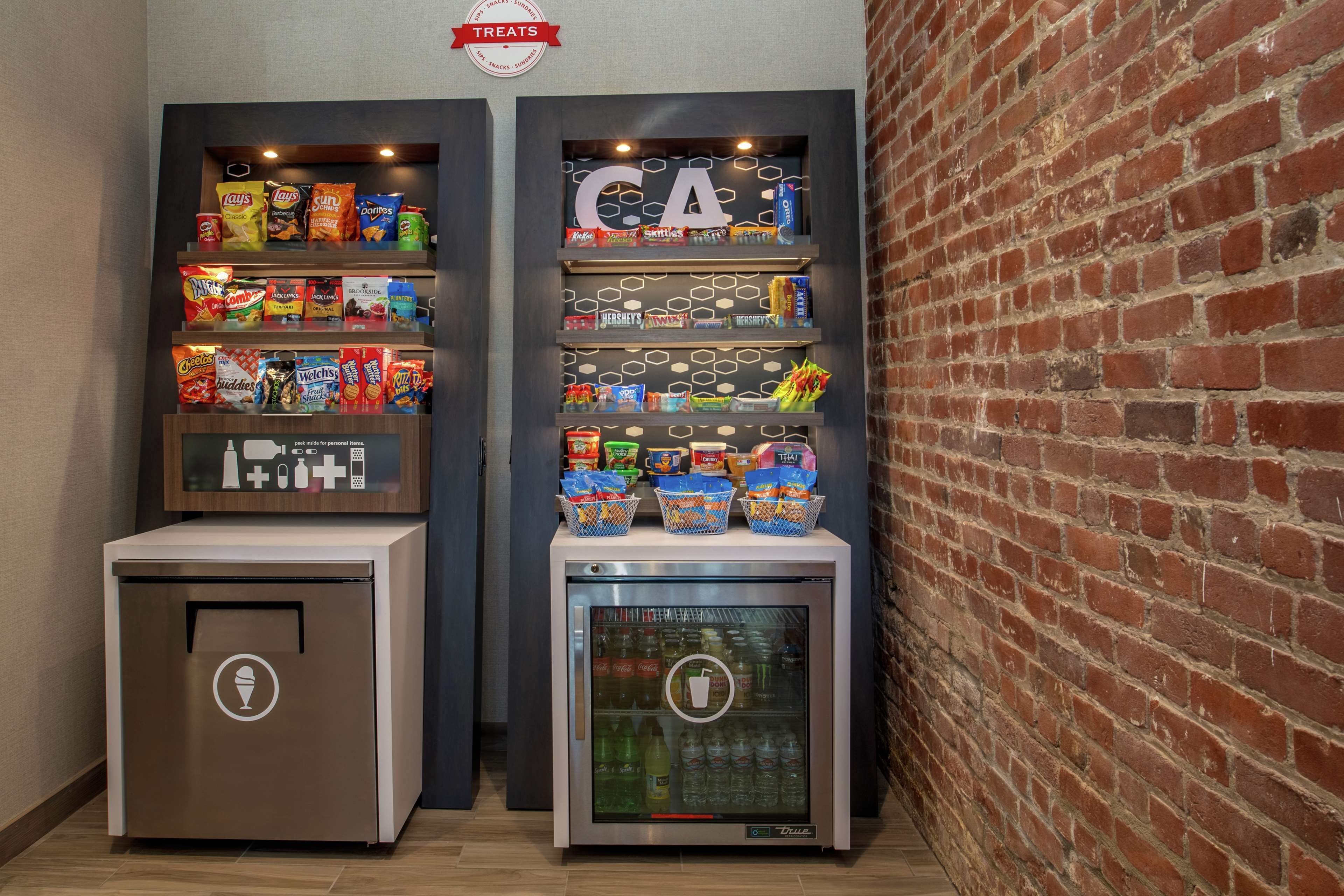 Een automaat voor snacks met diverse soorten snacks en een koelkast gevuld met drankjes.