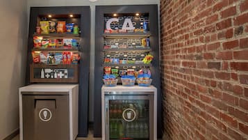 Een automaat voor snacks met diverse soorten snacks en een koelkast gevuld met drankjes.