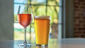 Dos vasos de bebidas sobre una mesa, con vista a follaje y un muro de ladrillo al fondo.
